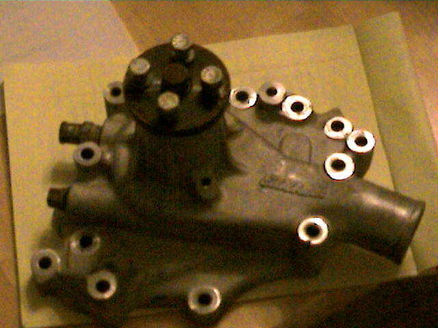 Close-up of a metal water pump with several bolts and ports