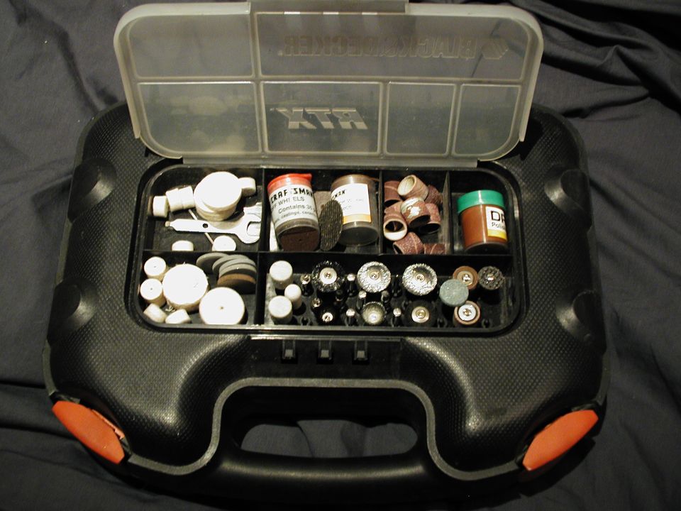 Open black plastic organizer case filled with rotary tool bits, sanding drums and small jars