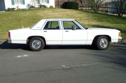 1991 Ford Crown Victoria LTD - Side profile of a white 1991 Ford Crown Victoria LTD sedan parked on a street.