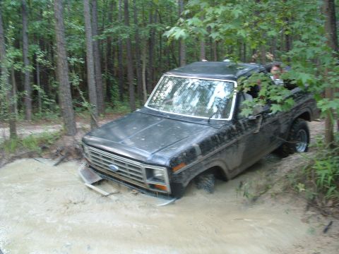 1993 Ford Bronco - This Ford Bronco is stuck in the mud, with trees and foliage surrounding it.