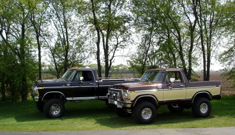 1979 Ford F-250 - Two Ford pickup trucks are parked side-by-side on a grassy lawn with trees in the background.