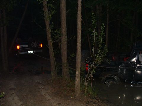 1993 Ford Bronco - Two SUVs are stuck in the mud at night, with one appearing to be towed by the other.