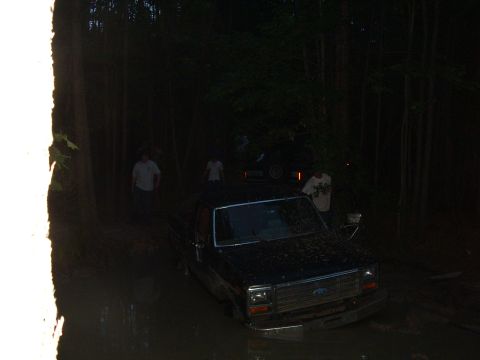 1993 Ford Bronco - Ford truck stuck in mud at night with several people observing.