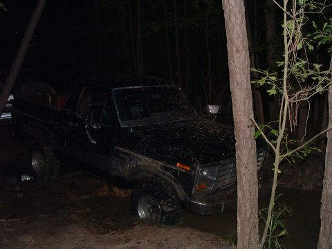 1993 Ford Bronco - This black Ford Bronco appears to be stuck in the mud during a nighttime off-road excursion.
