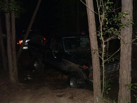 1993 Ford Bronco - Black Ford Bronco navigating rough terrain at night, with another vehicle in the distance.