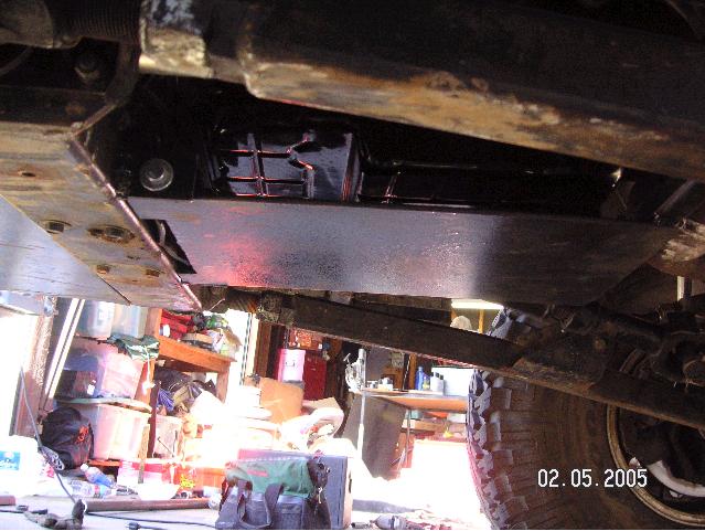 Undercarriage of a vehicle with a skid plate, suspension components, and a tire visible. A date stamp reads 02.05.2005