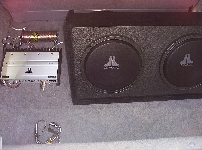 JL Audio amplifier and dual subwoofer box in car trunk