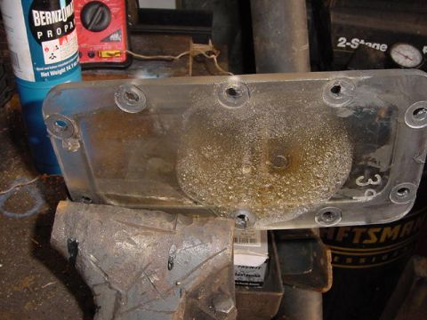 1971 Ford Bronco - A clear plastic automotive part is secured in a vise, with various tools and canisters in the background.
