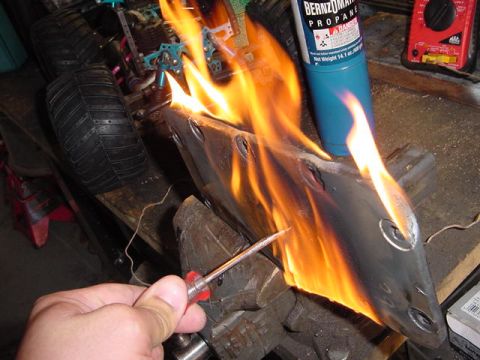 1971 Ford Bronco - Metal part being heated with a propane torch, held in a vise.