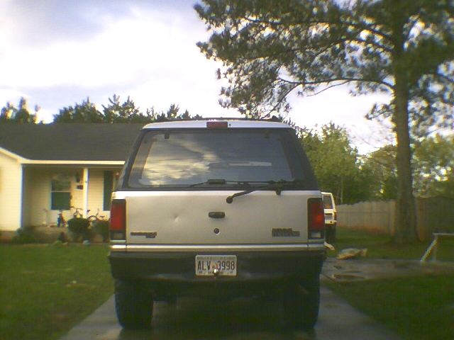 Rear of white two-door SUV parked in driveway with plate ALV-3998