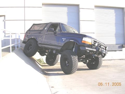 1994 Ford Bronco - A modified 1994 Ford Bronco is shown on a concrete ramp with a building in the background.