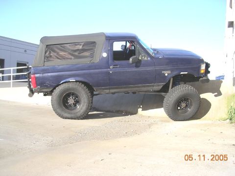 1994 Ford Bronco - This modified Ford Bronco, likely from the early to mid-1990s, is shown with a lifted suspension and large off-road tires.