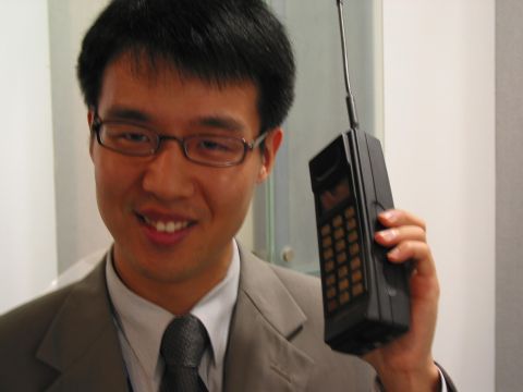 1990 Ford Bronco - Man holds a vintage brick cell phone, a relic from early mobile communication technology.