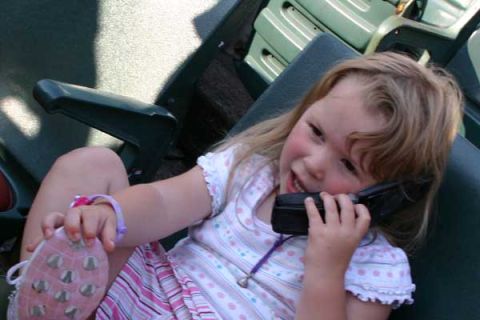1990 Ford Bronco - A young child sits in stadium seating, holding a phone to her ear and a pink shoe in her hand.
