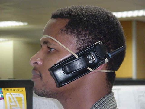 1990 Ford Bronco - A man improvises a hands-free device using a walkie-talkie and rubber bands.