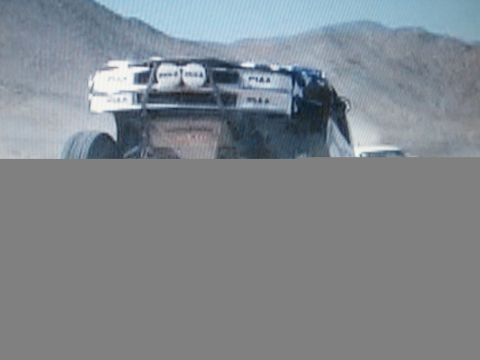 1990 Ford Bronco - off-road race truck jumps in the desert with a PIAA-labeled roof light bar; the lower portion of the frame is cut off.