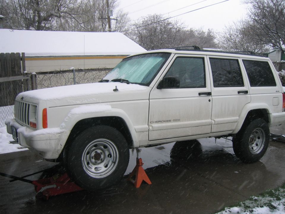 White 1997 Jeep Cherokee on jack stands in snow, front 3/4 view