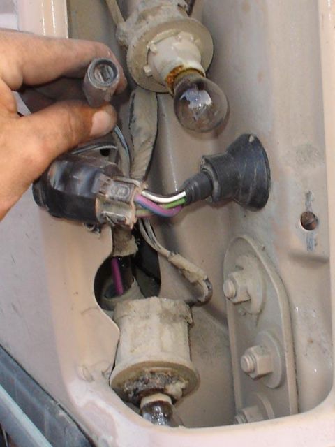1995 Ford Bronco - Close-up of a vehicle's tail light assembly, showing exposed wiring and bulbs during maintenance.