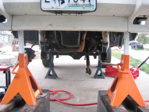 1997 Jeep Cherokee - The underside of a vehicle is visible, supported by jack stands, with parts of the drivetrain exposed.