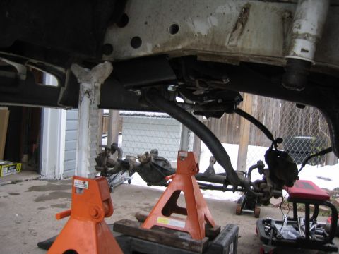 1997 Jeep Cherokee - The vehicle's undercarriage is visible, supported by jack stands, with snow on the ground.