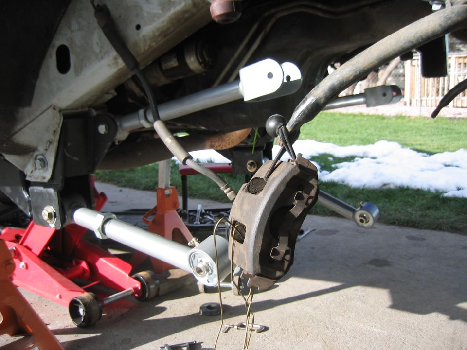1997 Jeep Cherokee XJ front suspension with brake caliper removed, showing upgraded control arms and sway bar disconnects