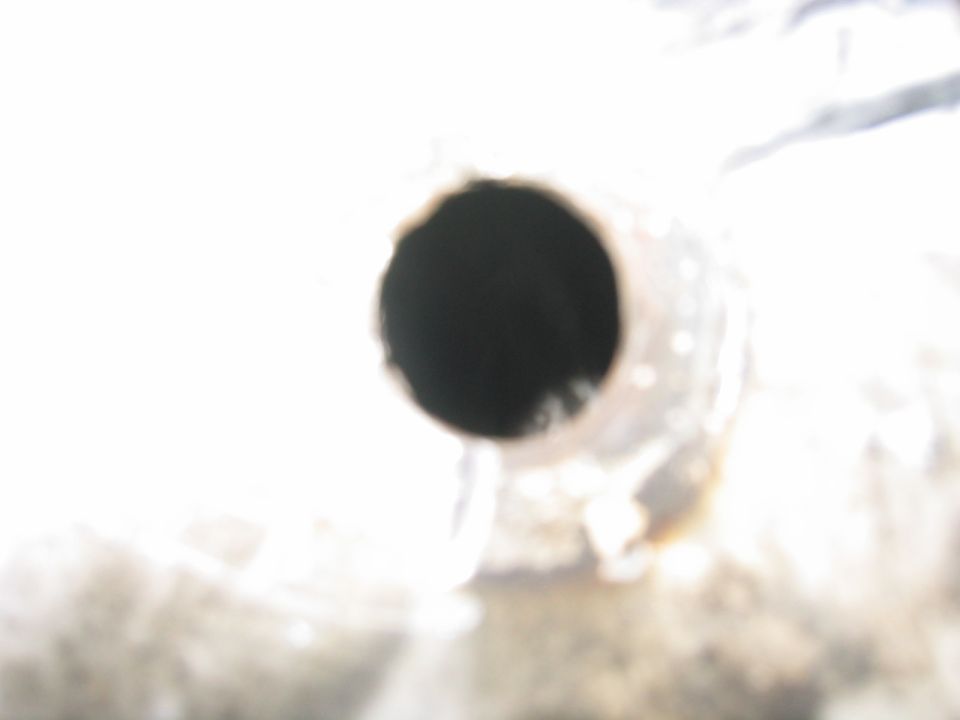 Close-up of a dark, circular opening of an exhaust pipe
