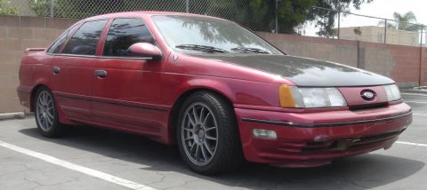 1991 Ford Taurus - This red sedan has a carbon fiber hood and aftermarket wheels.