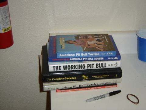 1988 Ford Bronco - A collection of books related to pit bulls and dogs is piled on a shelf, with a fire extinguisher visible to the left.