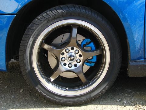 2002 Subaru Impreza - Close-up of a blue car's wheel aftermarket bronze rims and vibrant blue brake calipers.