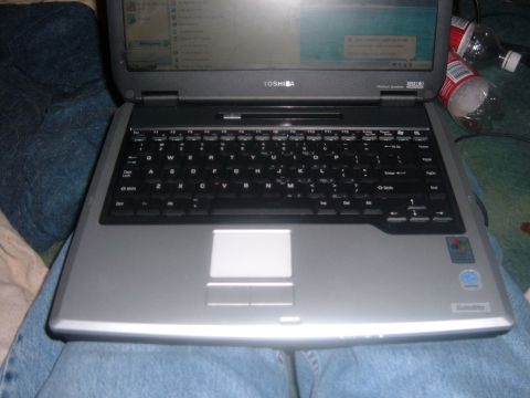 1985 Ford F-150 - A Toshiba Satellite laptop is shown with its keyboard and screen illuminated, resting on someone's lap.