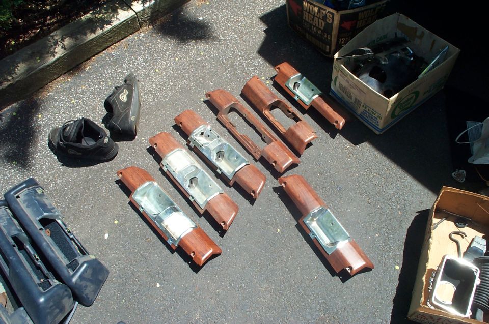 Woodgrain door trim panels laid out on a driveway with parts boxes nearby