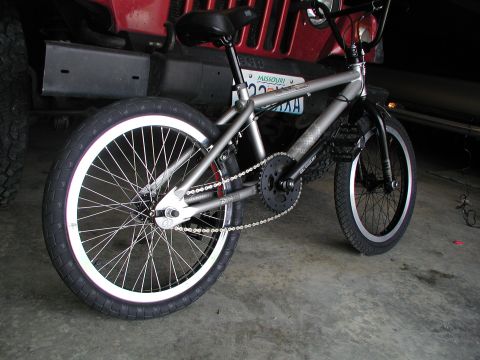 1998 Jeep TJ - A BMX bicycle is parked in front of a red Jeep, with a Missouri license plate visible on the Jeep.