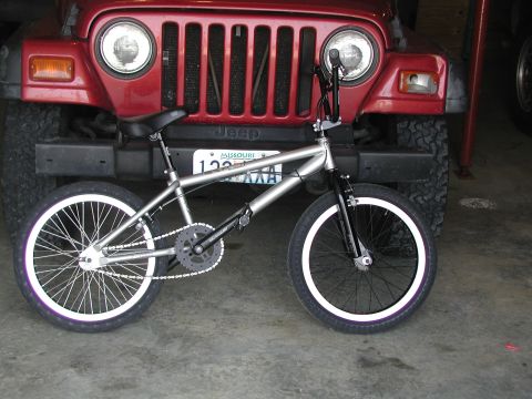 1998 Jeep TJ - A red 1998 Jeep TJ is parked behind a silver BMX bicycle.