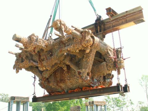 1988 Ford Bronco - Large, corroded metal structure being hoisted by a crane against a bright sky.