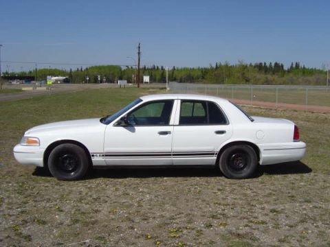 1998 Ford Crown Victoria - A white 1998 Ford Crown Victoria is shown from the side, parked outdoors on a sunny day.