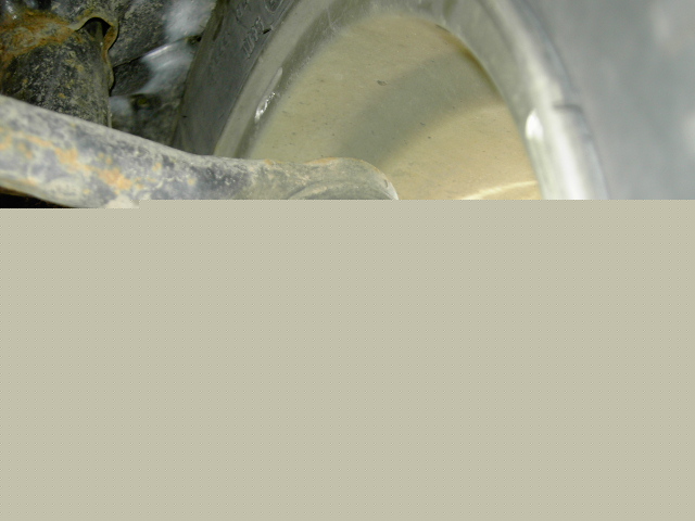 Close-up of a rusty suspension arm and part of a wheel well