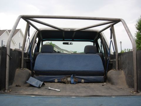 1995 Ford Bronco - The interior of a vehicle is shown with blue seats and a prominent roll cage structure.