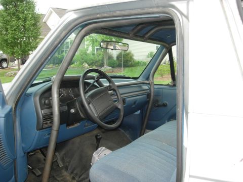 1995 Ford Bronco - The interior of a 1995 Ford Bronco features a prominent roll cage and blue cloth seats.