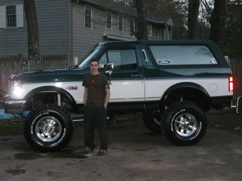1994 Ford Bronco - A person stands next to a lifted Ford Bronco, which appears to be from the early to mid-1990s.