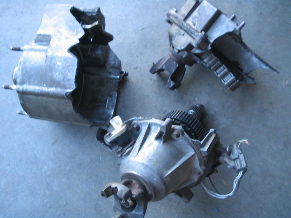 Three damaged transmission components on a gray surface