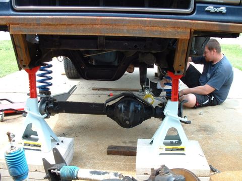 1995 Ford Bronco - Mechanic works on the suspension of a 1995 Ford Bronco, which is raised on jack stands.