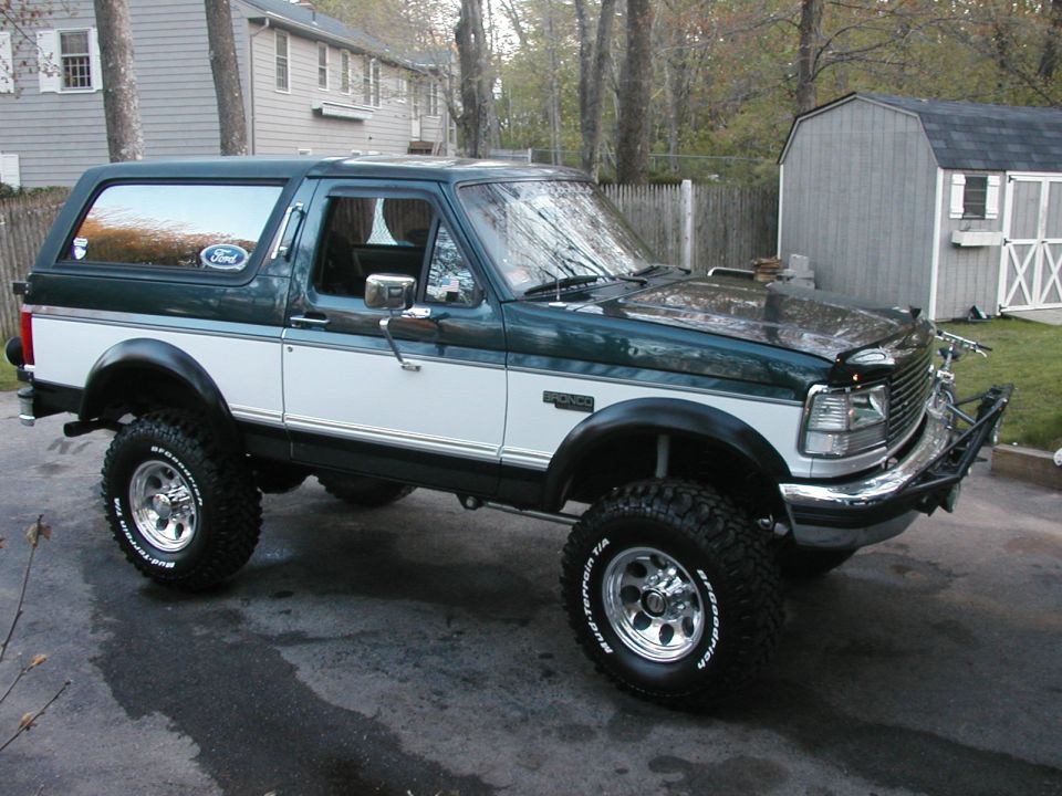 Green and white 1994 Ford Bronco with aftermarket bumper and large tires