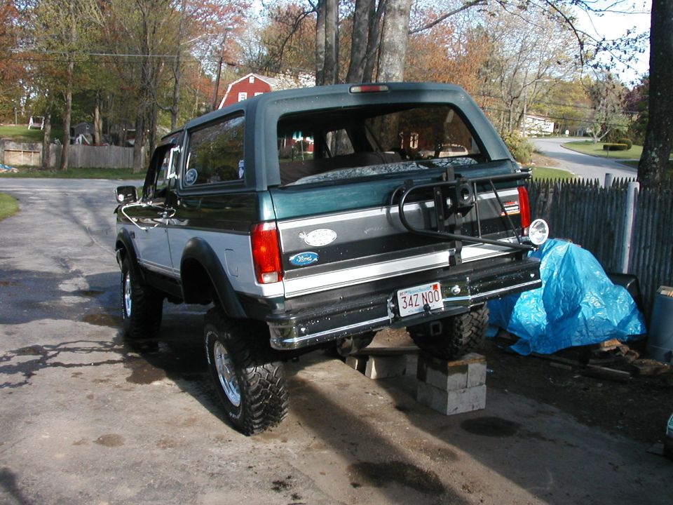 1992 Ford Bronco lifted on blocks, rear view. Spare tire carrier mounted on tailgate