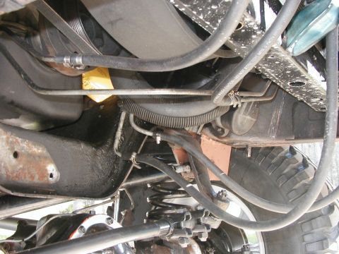 1994 Ford Bronco - Close-up view of the engine bay and suspension system of a vehicle, with various hoses and mechanical parts visible.