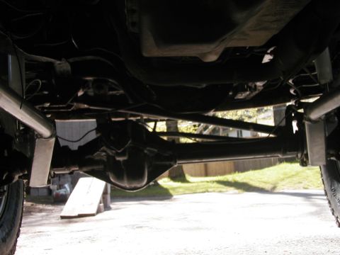 1994 Ford Bronco - A low-angle shot captures the underside of a vehicle, focusing on the rear axle and suspension system.