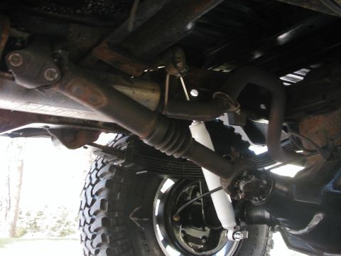 1994 Ford Bronco - Close-up view of the undercarriage, highlighting the suspension components and driveshaft of a vehicle.