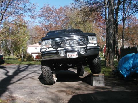1994 Ford Bronco - A modified black Ford Bronco is parked with its front wheels elevated on cinder blocks.