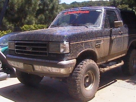 1991 Ford Bronco - This 1991 Ford Bronco is heavily covered in mud, obscuring some of its details but not its overall shape.