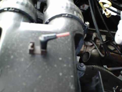 1987 Ford Bronco - Close-up view of engine components, including hoses and metal tubing, with a black connector in focus.