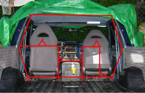 1985 Ford Bronco - Interior view of a truck bed with seats and dashboard, partially covered by a green tarp.
